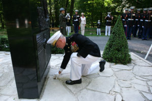 Gen. James F. Amos lays a commemorative coin in front of the Iron Mike monument in the heart of the Belleau Wood forest